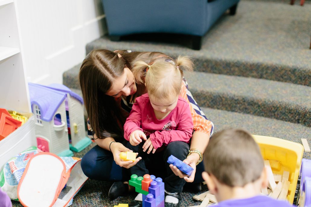 Adult holding child playing with large legos