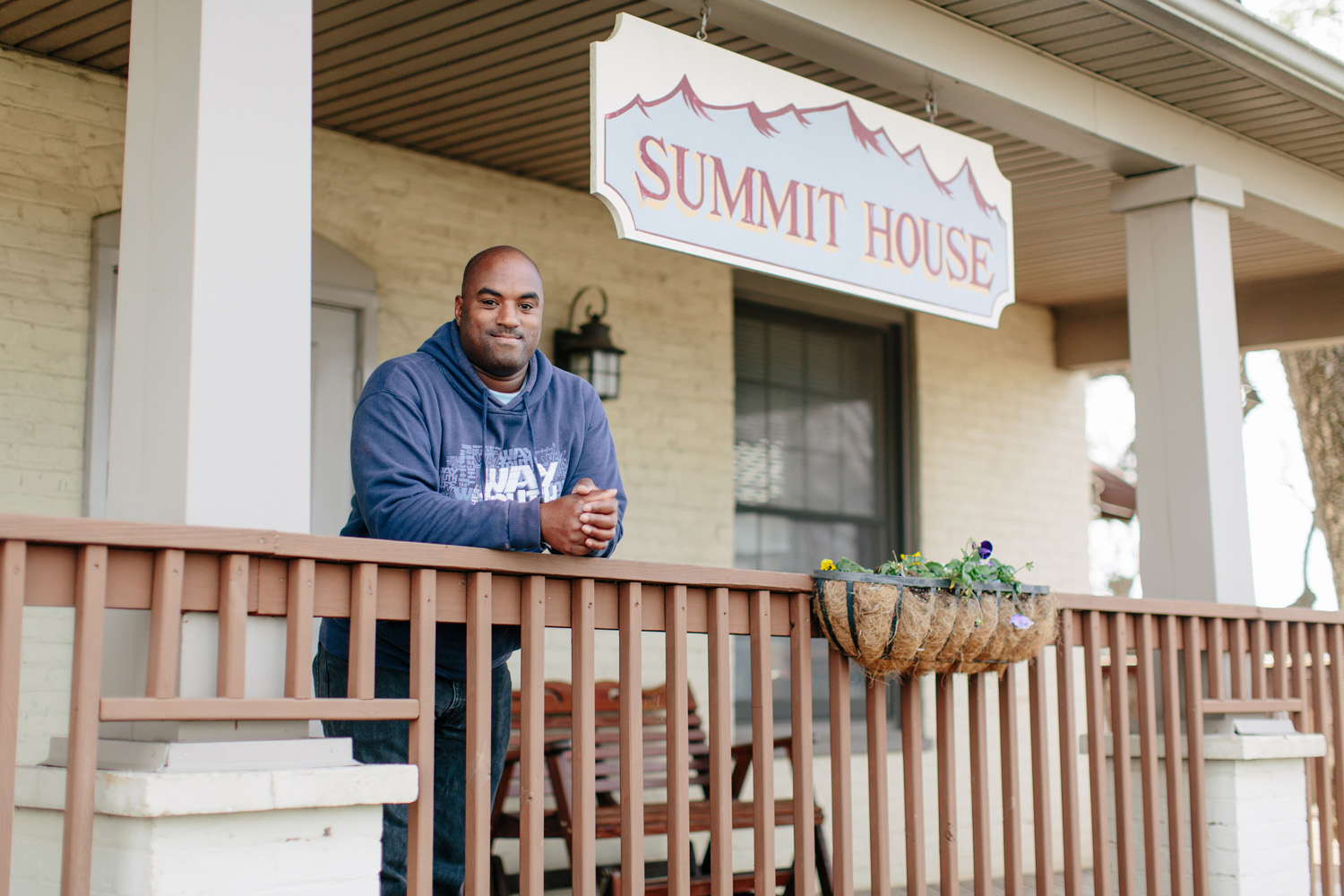 Man leaning on rail with sign that says Summit House